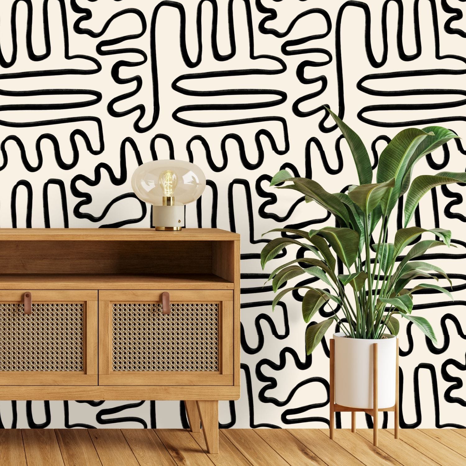 A zoomed-in of Painter’s Doodle wallpaper styled in a modern space with organic black line pattern and indoor plant.